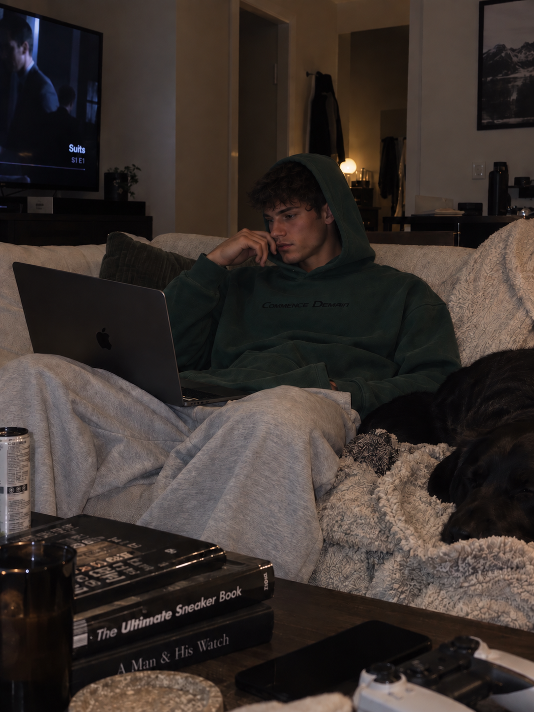 Guy wearing a Commence Demain hoodie while relaxing on the couch at night